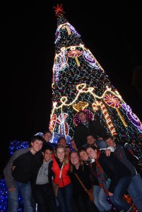 Choir members pose for a picture at the base of a Christmas tree that is next to the Royal Castle.
